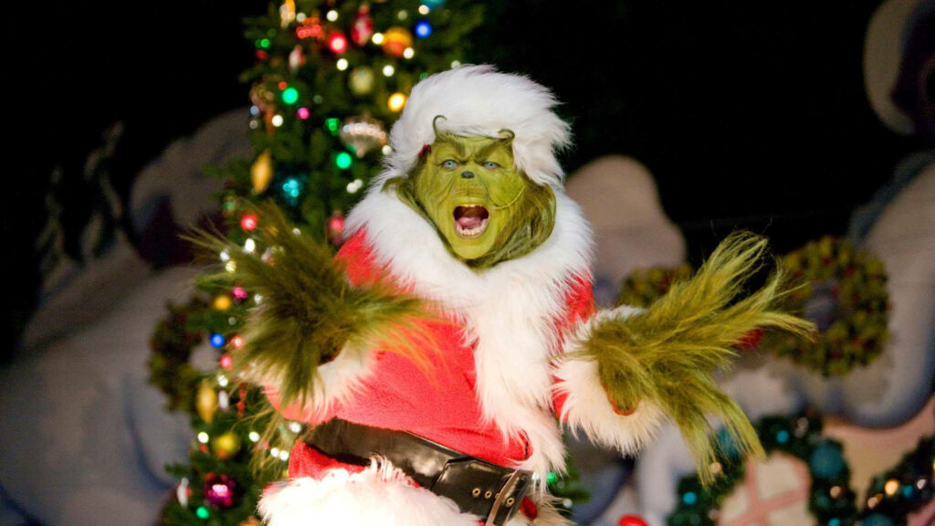 Joyful Grinch in Santa Outfit by Glowing Christmas Tree Wallpaper