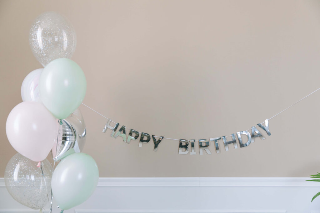 Festive Happy Birthday Banner with Pastel Balloons on Neutral Background Wallpaper