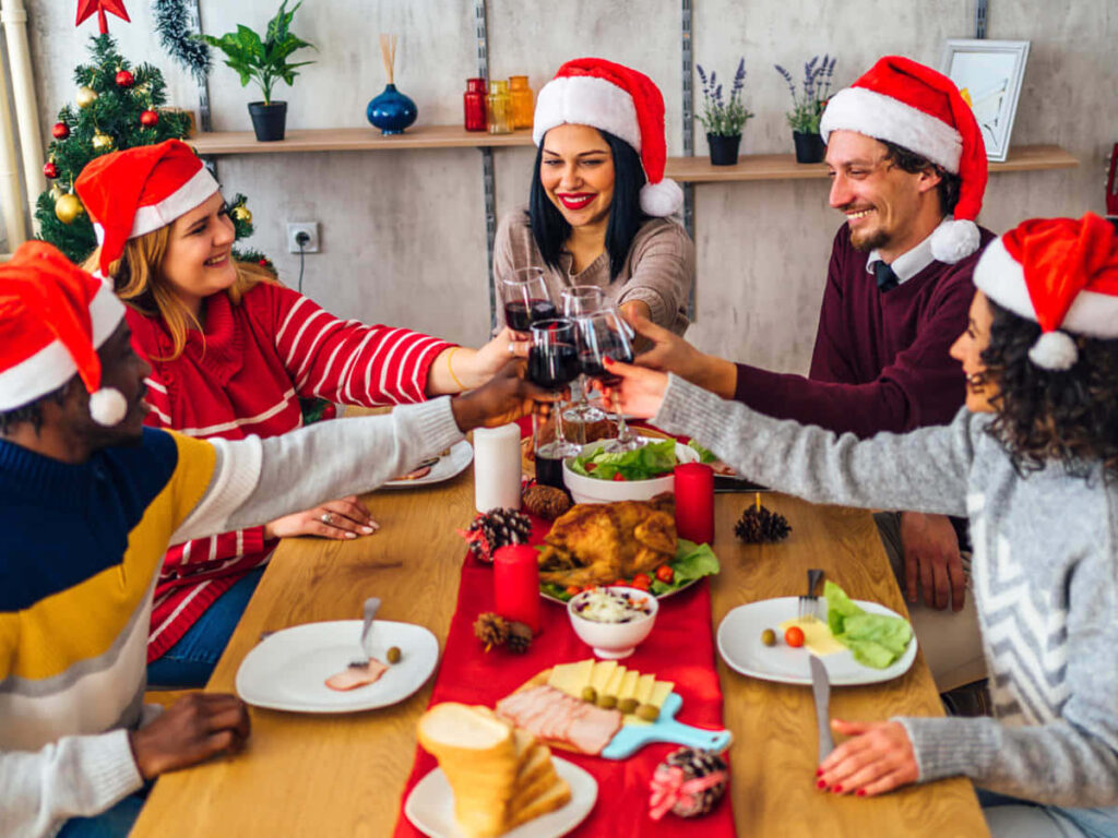 Joyful Holiday Celebration: Friends Toasting at Festive Table Wallpaper