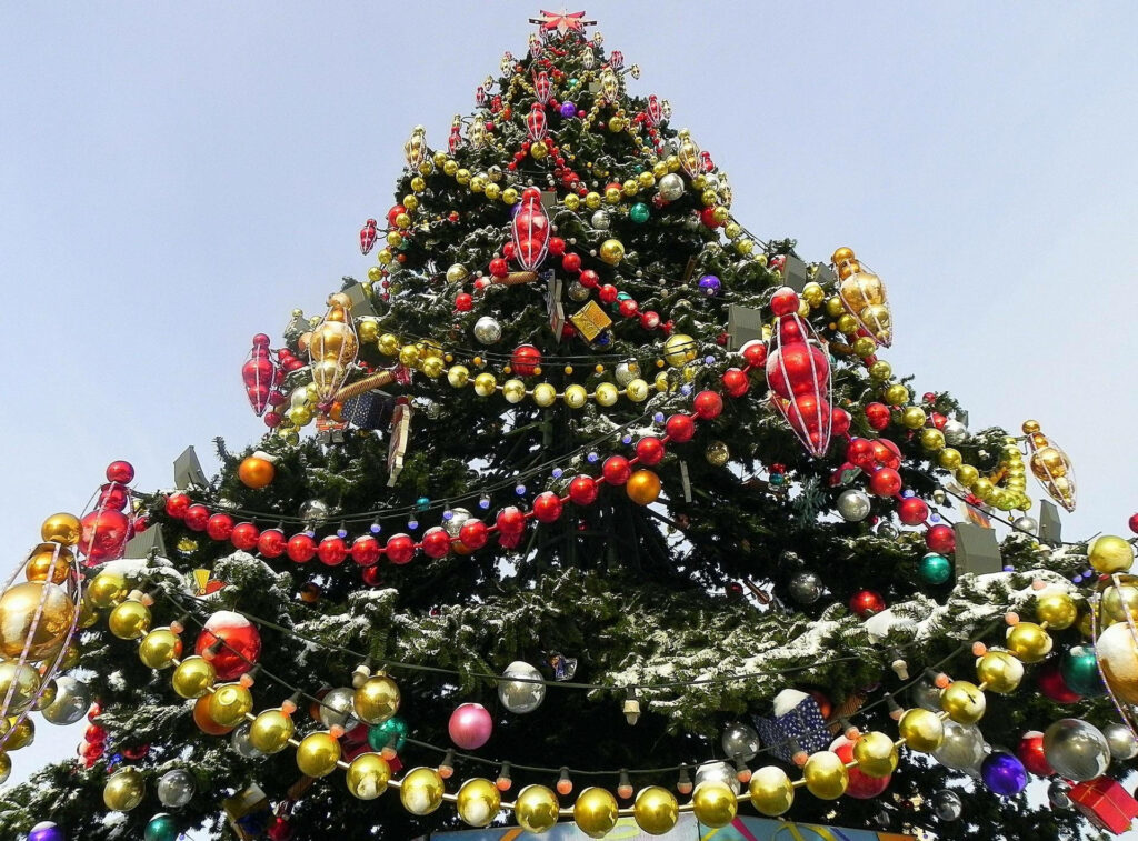 Festive Elegance: Mesmerizing Christmas Tree adorned with a Kaleidoscope of Ball Garlands sets the stage for Joyous Holiday Celebrations Wallpaper