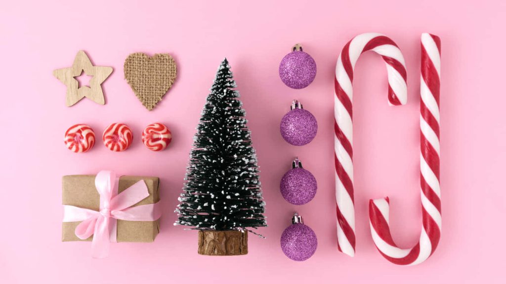 Festive holiday flat lay with snowy mini tree candy canes purple baubles gift box peppermint Wallpaper