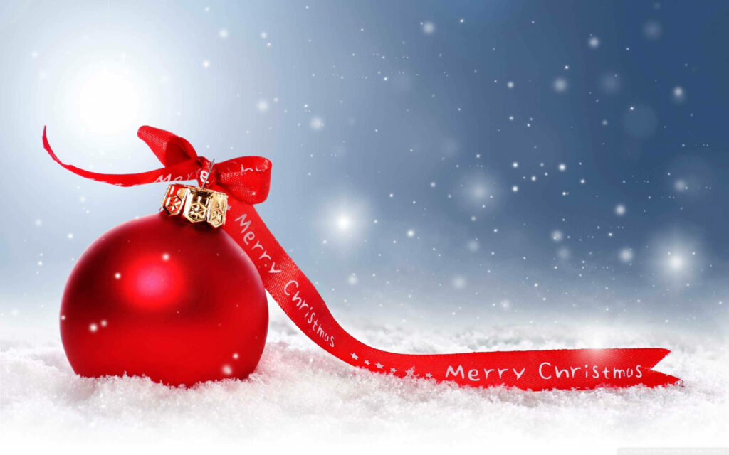 Festive Red Christmas Ball with Ribbon in Snowy Holiday Scene Wallpaper
