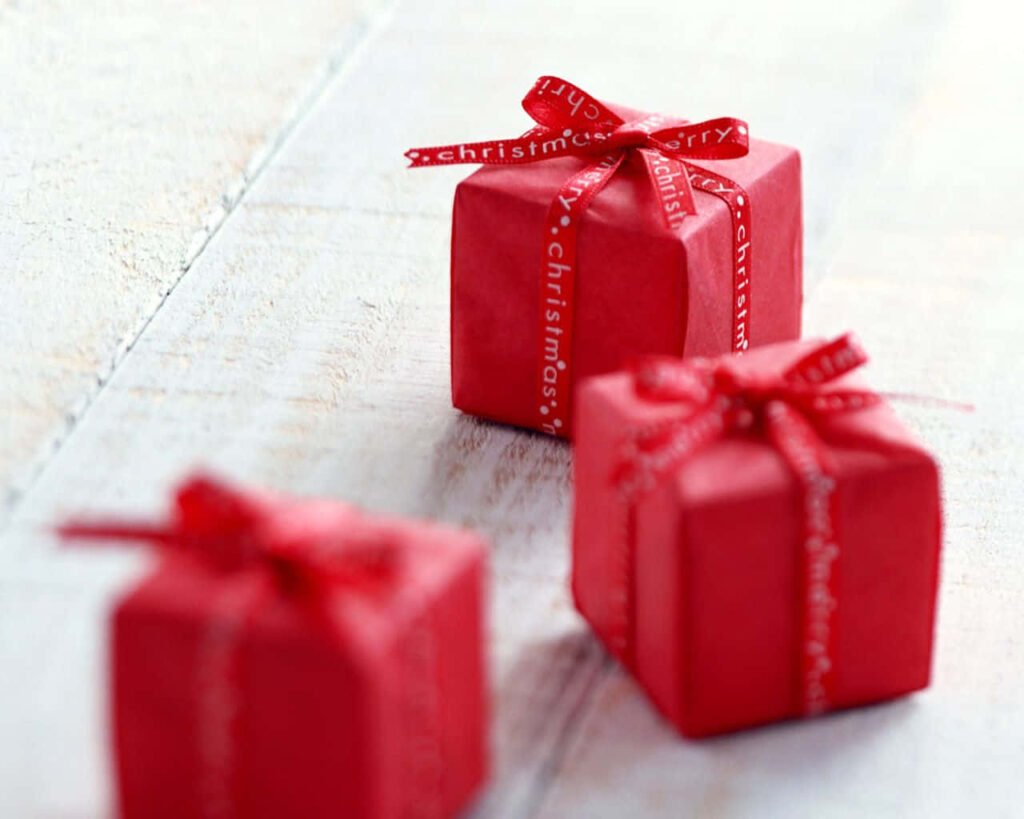 Three small red gift boxes with ribbons festive holiday season celebration wallpaper background