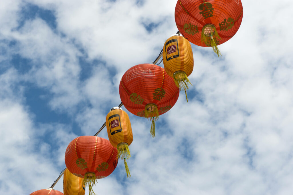 Bright red and gold Chinese New Year lanterns against blue sky festive celebration background Wallpaper