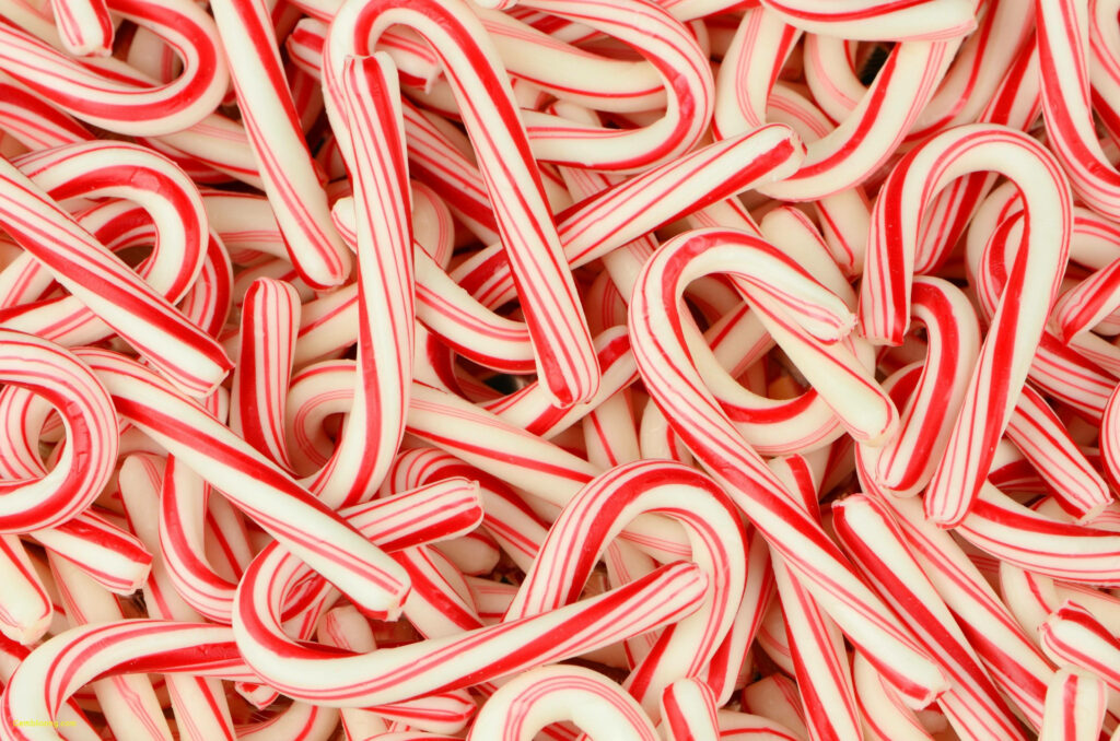 Festive red and white candy cane pattern wallpaper background with glossy bold stripes and holiday cheer
