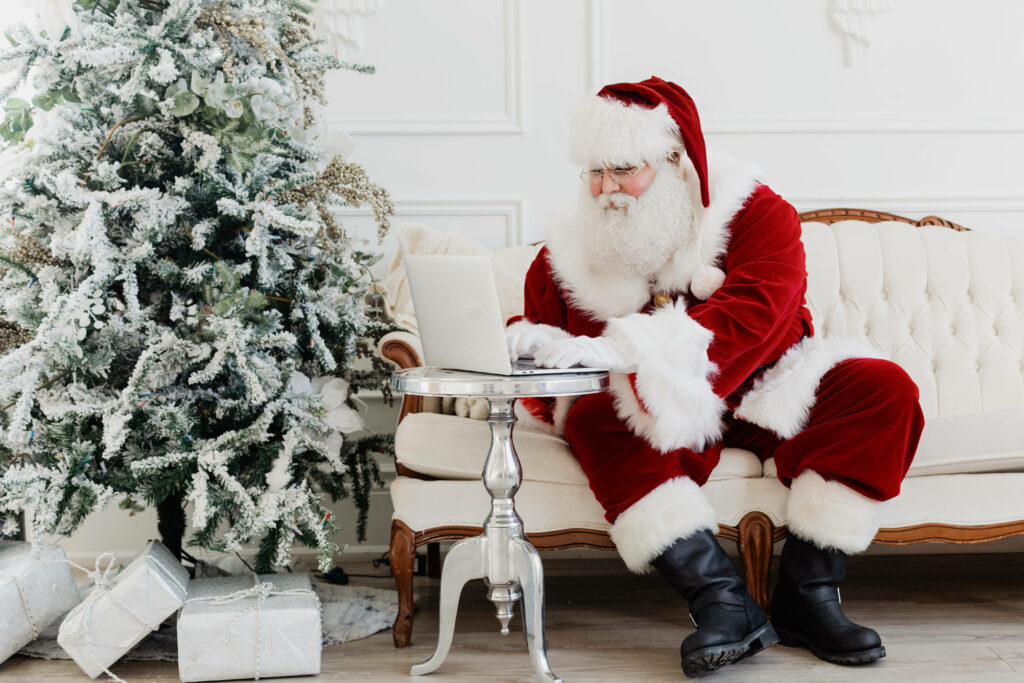 Festive Santa on White Sofa with Christmas Tree & Gifts Wallpaper