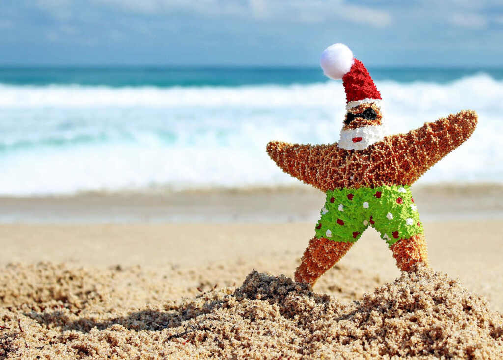 Cheerful Santa Starfish on Sunny Beach with Ocean Waves Wallpaper