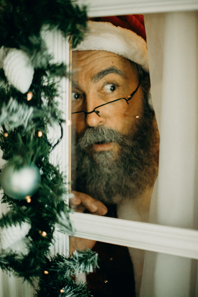 Festive Santa Hat Man Peering Through Holiday Window with Ornaments Wallpaper