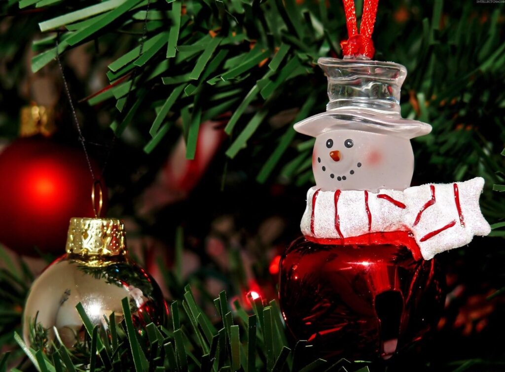 Festive Snowman Ornament Wallpaper: Holiday Cheer Among Green Branches