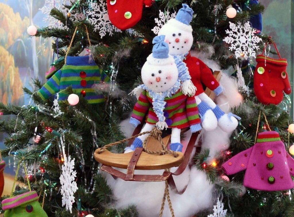 Adorable Snowmen on Sled with Festive Christmas Tree Wallpaper