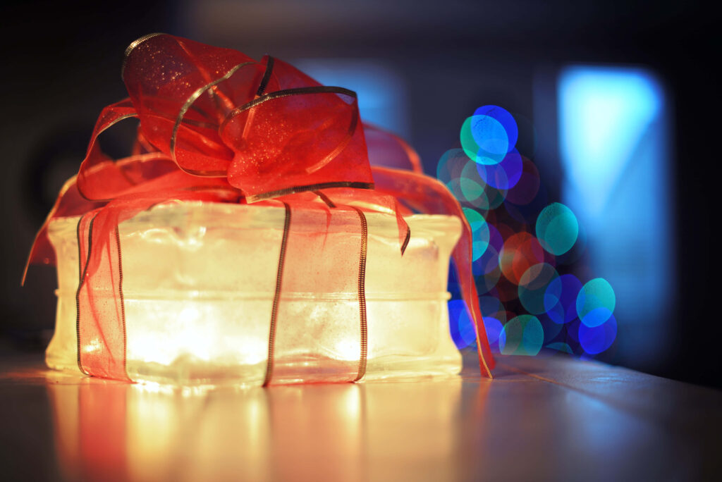 Festive Gift with Glowing Red Ribbon & Colorful Bokeh Background Wallpaper