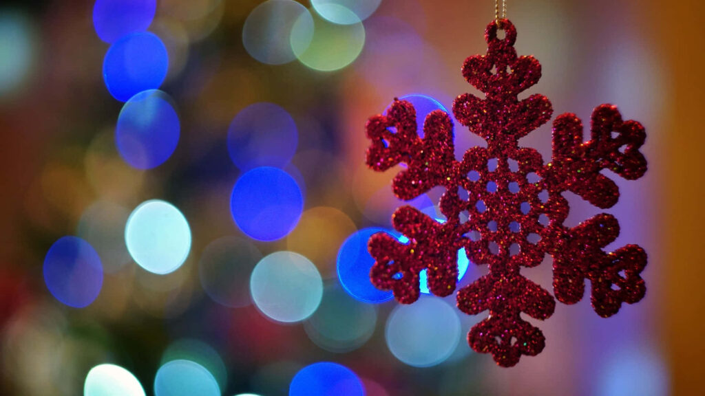 Red Snowflake Ornament Over Colorful Holiday Lights - Festive Wallpaper