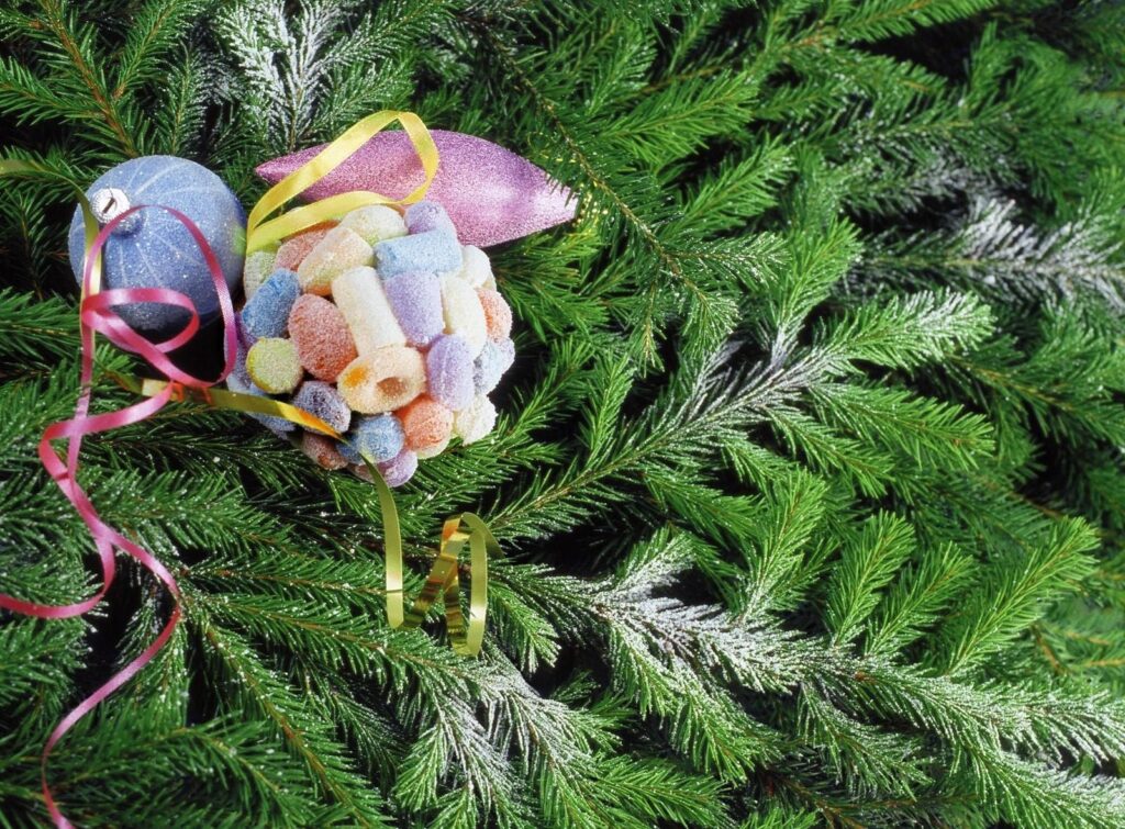 Festive Wallpaper: Lush Green Tree Needles with Snowy Christmas Toys