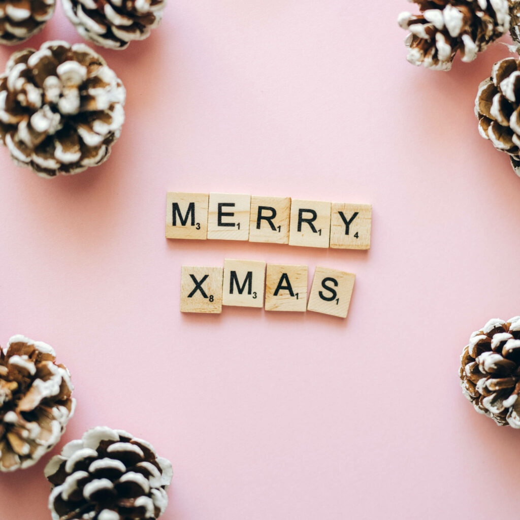 Festive Wallpaper: Scrabble Tiles MERRY XMAS on Pink with Pinecones