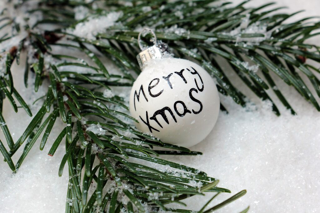 Festive Snow-Dusted Spruce Branch with Merry Xmas Ornament Wallpaper