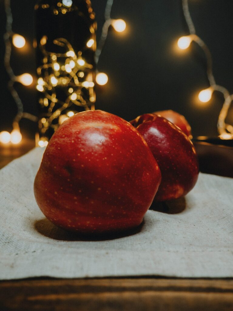 Vibrant Red Apple Wallpaper with Decorative String Lights Glow