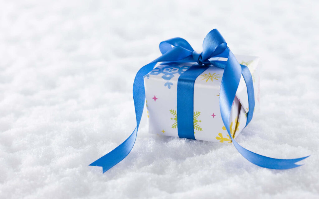 Blue ribbon gift box on sparkling snow festive winter scene wallpaper background