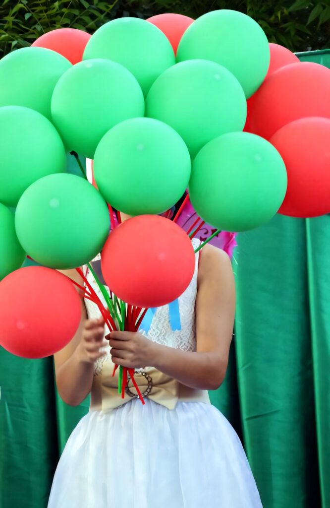 Festive Woman with Red and Green Balloons Against Green Fabric Wallpaper