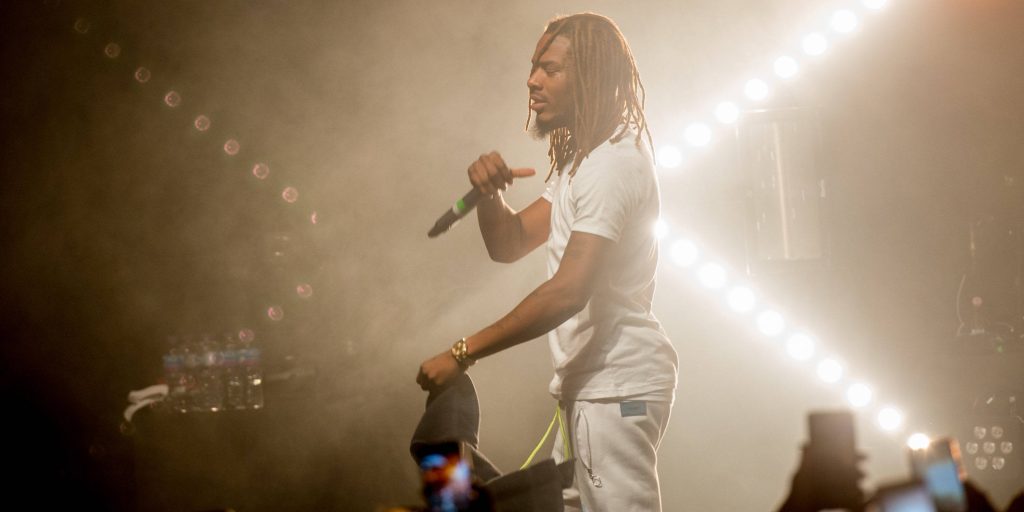 Fetty Wap performing live in all white with bright stage lights and hazy concert background Wallpaper