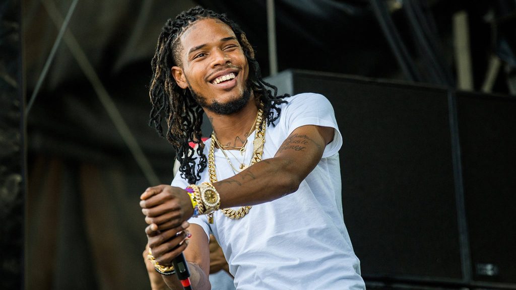 Fetty Wap smiling on stage in white tee gold chains vibrant hip-hop concert wallpaper background
