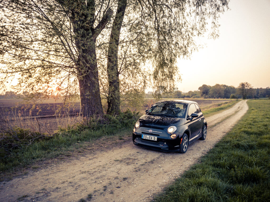 Charming Black Fiat 500e on Serene Rural Road - Countryside Background Wallpaper