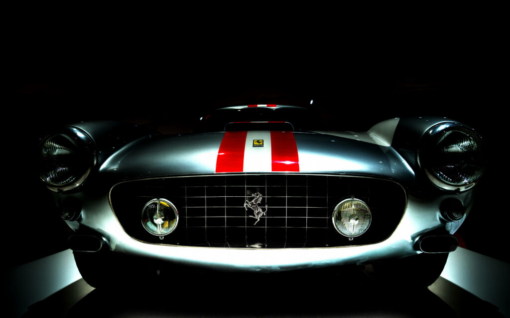 Sleek and Powerful: Captivating HD Car Background with a Ferrari Emblem on a Shadowed Red and White Painted Hood Wallpaper