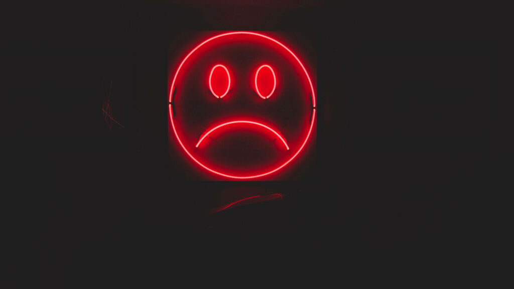 Moody and Striking Emo Wallpaper: Neon Red Unhappy Face in Dark Room