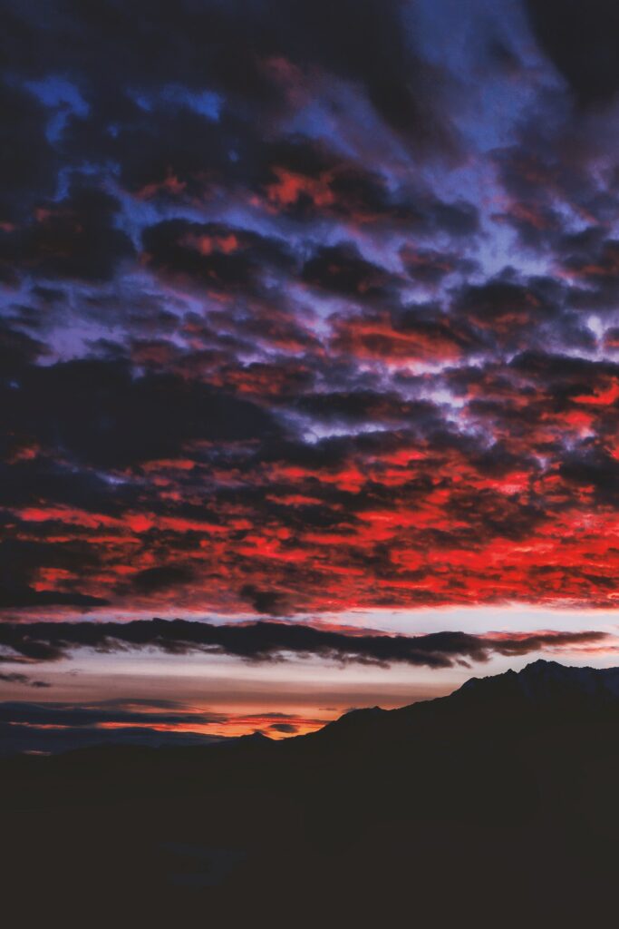 Dramatic night mountain wallpaper with fiery red and purple clouds over dark peaks