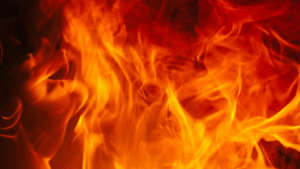 Close-up vibrant fire wallpaper with dancing yellow orange and red flames providing warmth