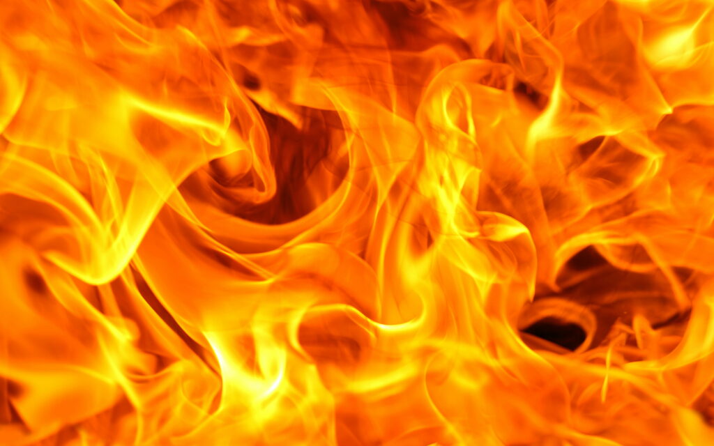 Close-up vibrant orange and yellow flames swirling in a dynamic blazing bonfire macro photo wallpaper