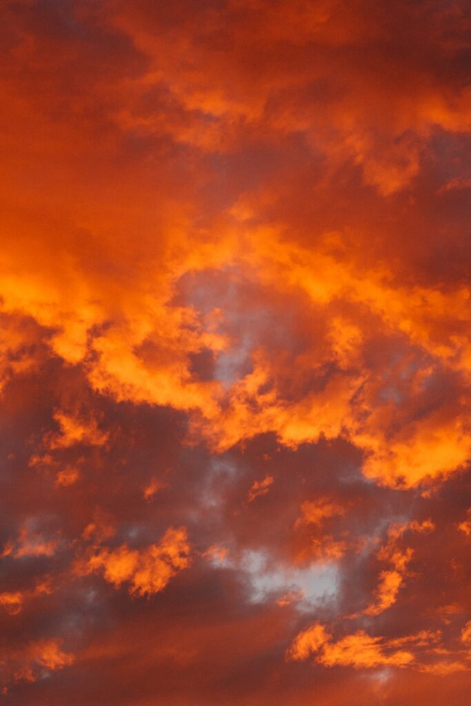 Fiery orange clouds with porous texture create a vibrant warm sky wallpaper background