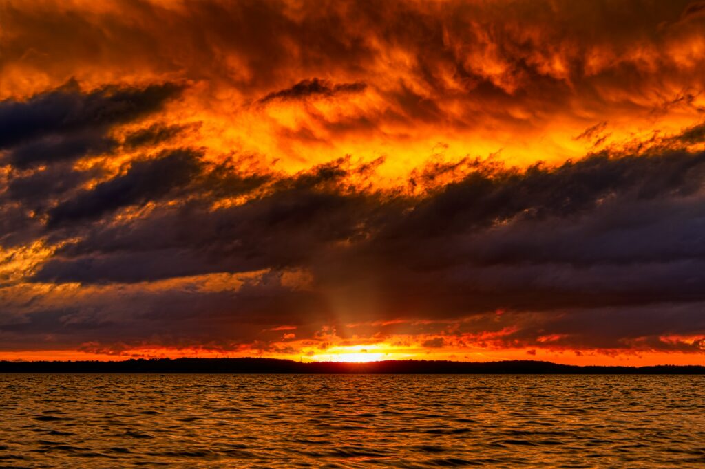 Fiery orange red sunset over calm sea with golden reflections and dramatic colorful horizon wallpaper