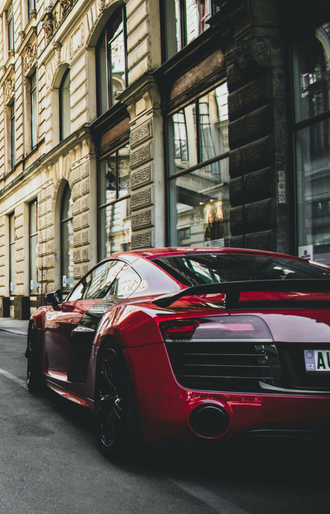 Fiery red Audi R8 parked on stylish city street showcasing luxury sports car design wallpaper