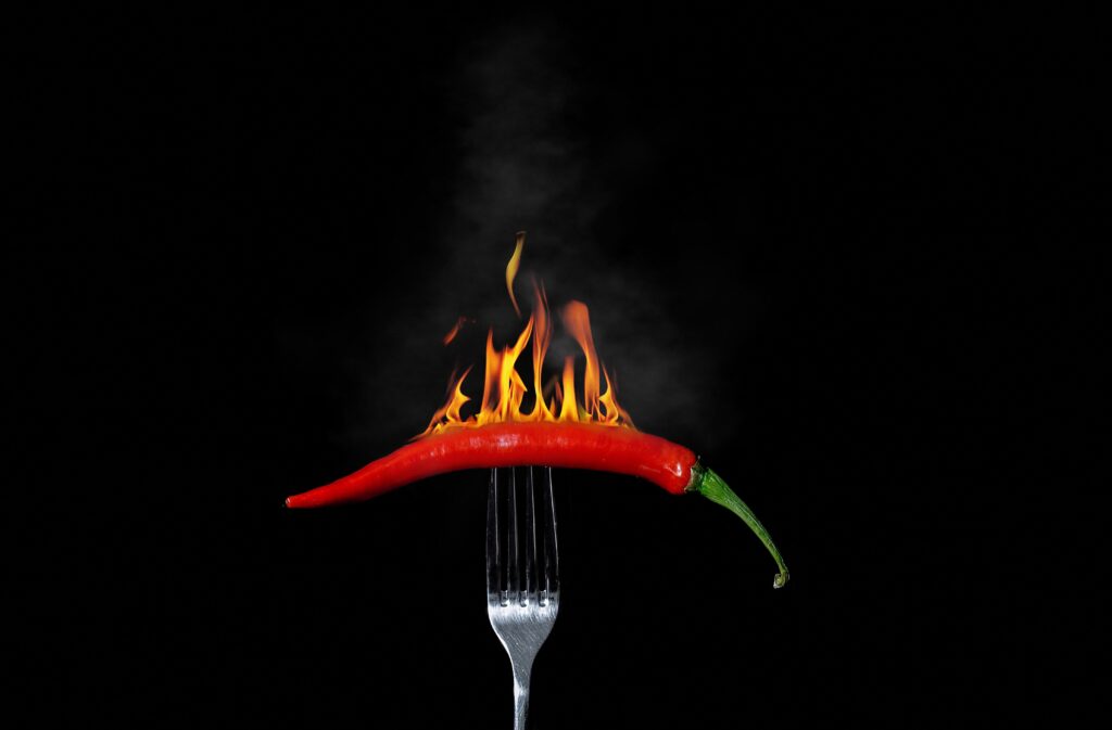 Fiery Red Chile Pepper on Fork: Intense Heat Wallpaper Background