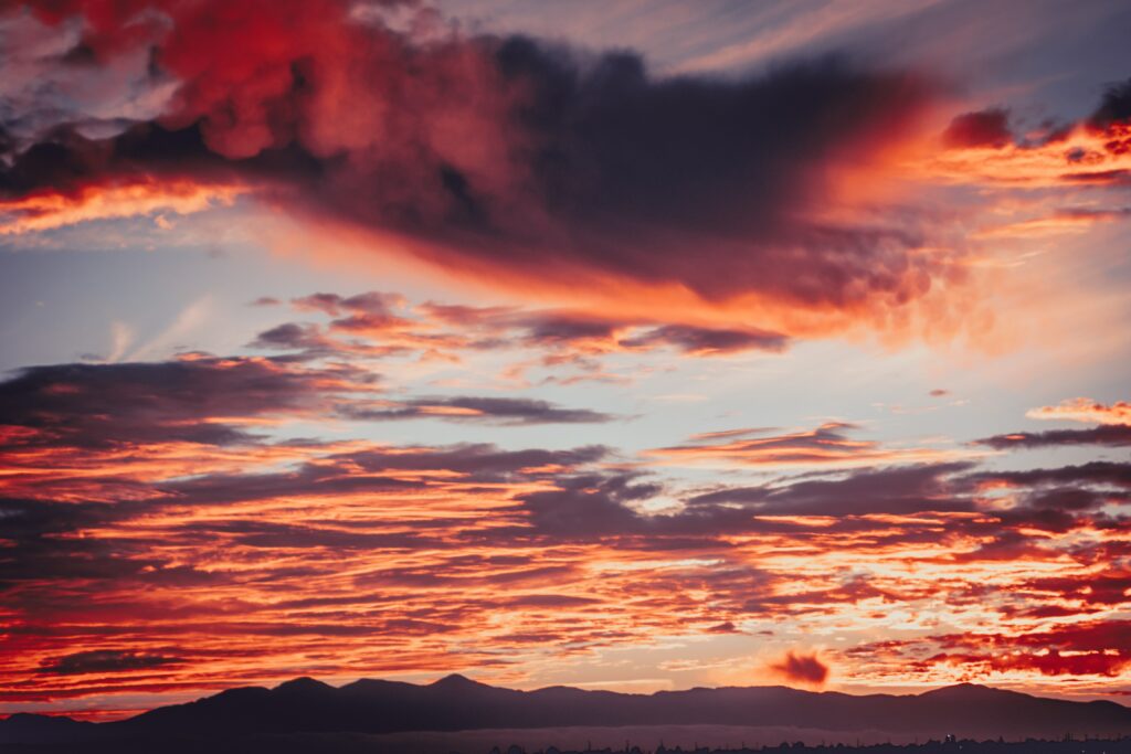 Fiery red sunset with dramatic clouds over dark mountain silhouettes vibrant warm sky wallpaper