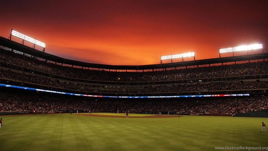 Baseball stadium at dusk with glowing floodlights and vibrant fiery sunset sky wallpaper