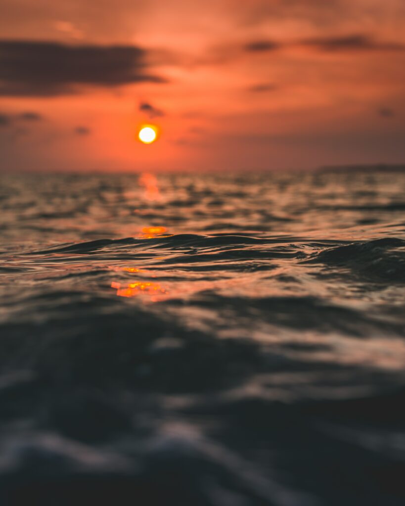 Sunset over rippling sea waves with fiery orange sky and warm red gold reflections wallpaper