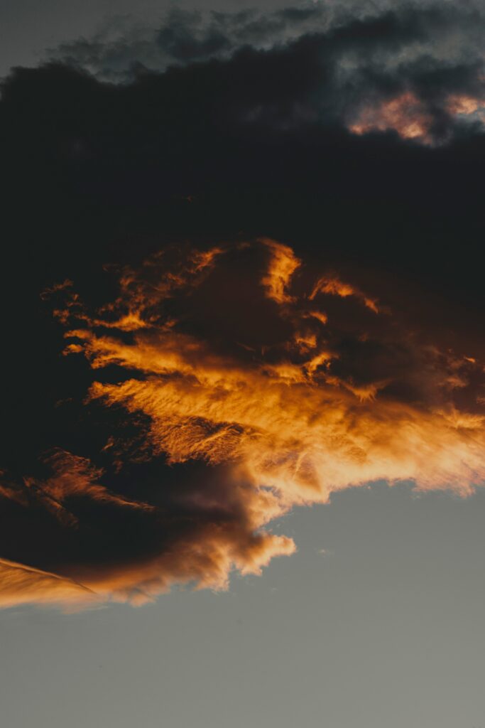 Fiery sunset with dark dramatic clouds and deep shadows creating a striking wallpaper background
