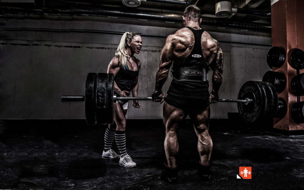 Muscular man lifting heavy weights with determined woman encouraging him Find your strength wallpaper