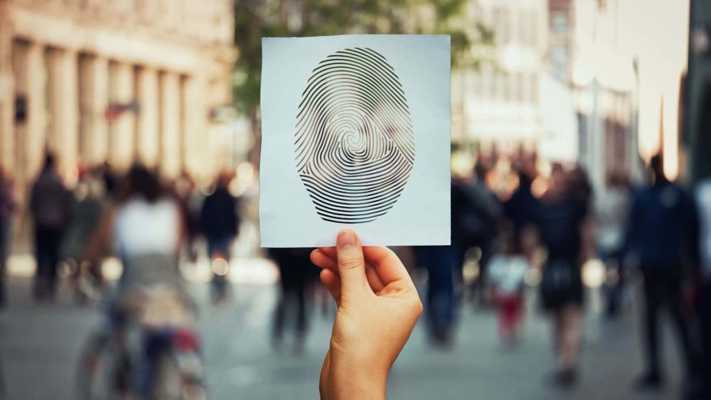 Hand holding white card with fingerprint cutout city street background identity tech theme wallpaper