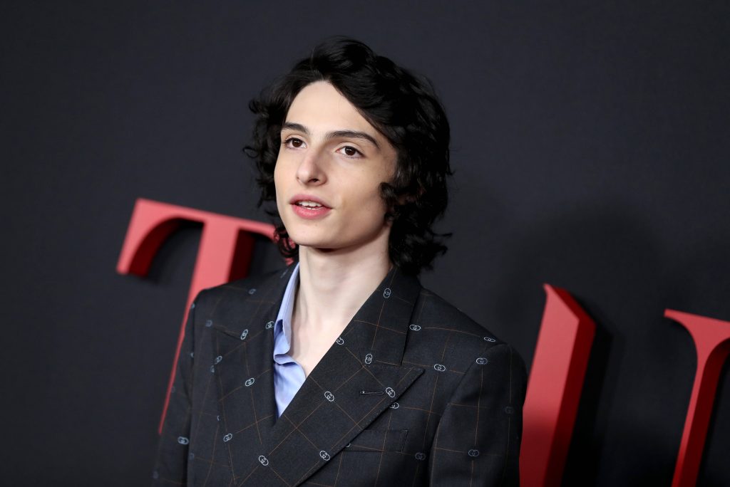 Finn Wolfhard in patterned suit jacket blue shirt red carpet portrait dark event backdrop wallpaper