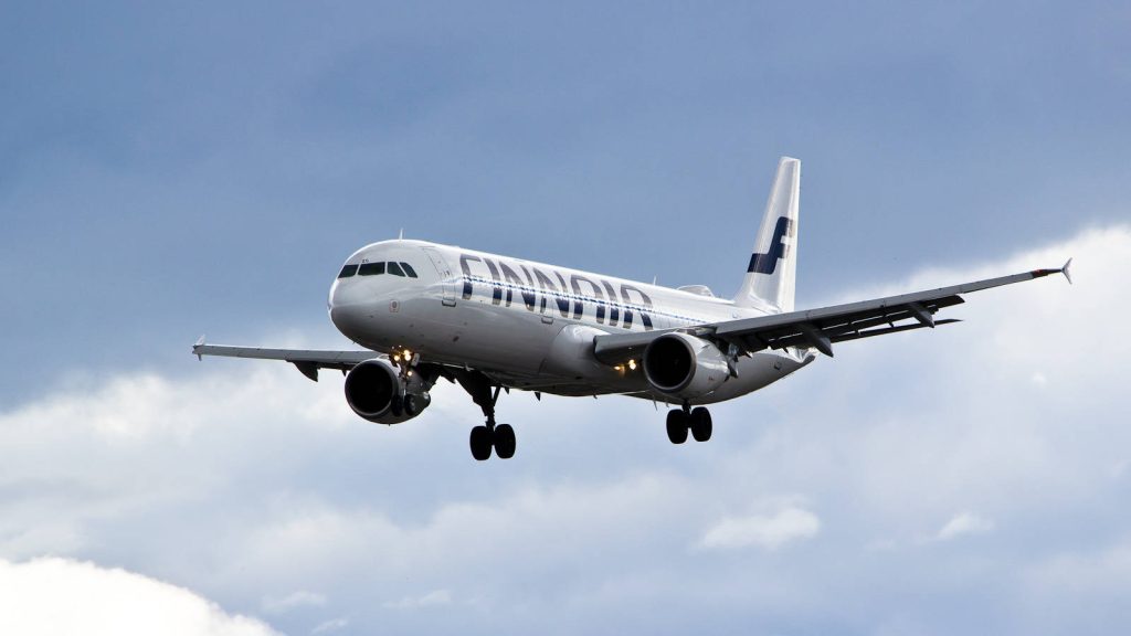 Finnair aircraft landing against vibrant blue sky with white clouds aviation wallpaper background