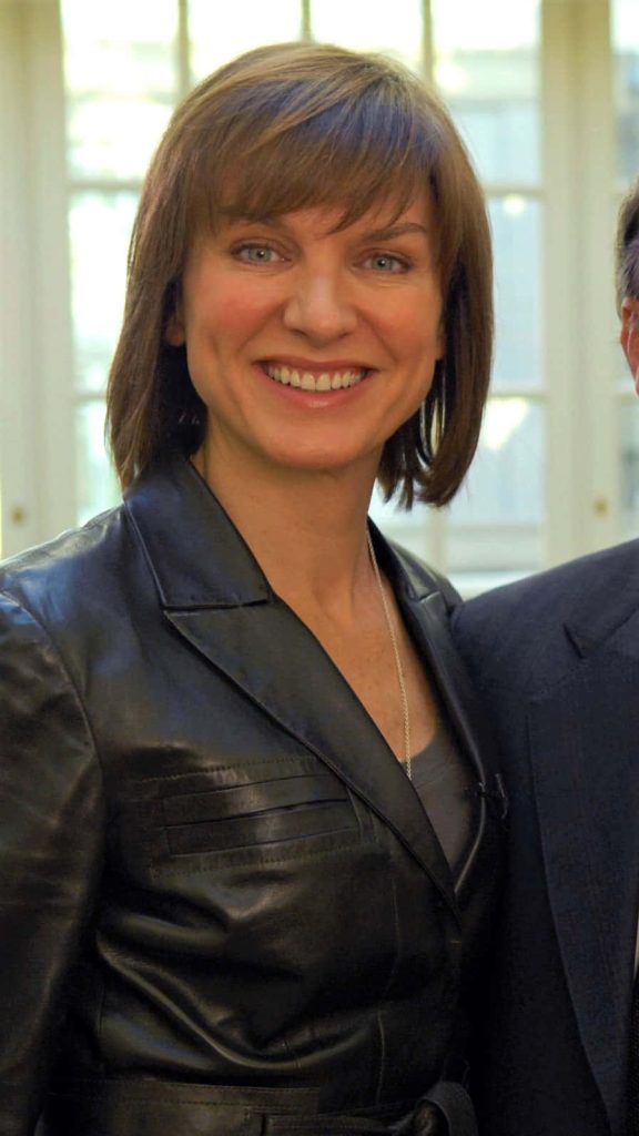 Fiona Bruce smiling in black leather jacket bright natural light windowed background wallpaper