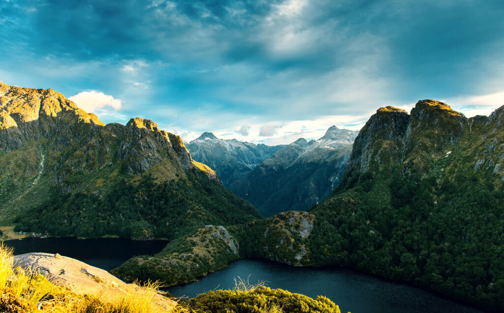 Fiordland National Park sunrise with rugged mountains lush forests and reflective tranquil lake wallpaper
