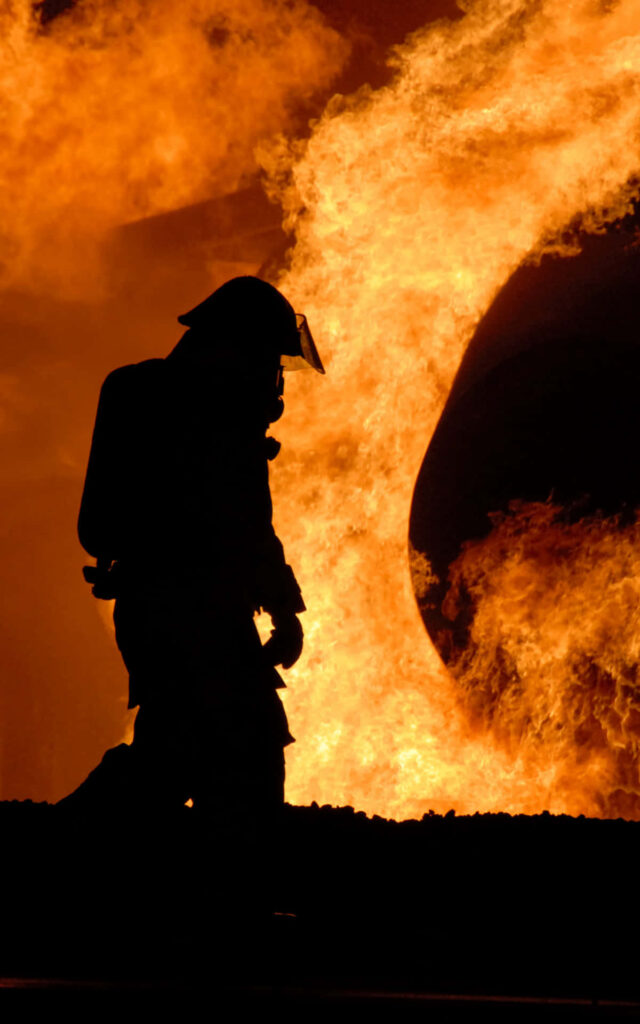 Silhouetted firefighter battling intense ring of fire dramatic flames wallpaper background