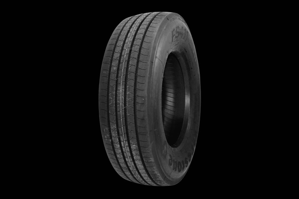 Firestone FS411 commercial tire with bold tread and sidewall branding on black background Wallpaper