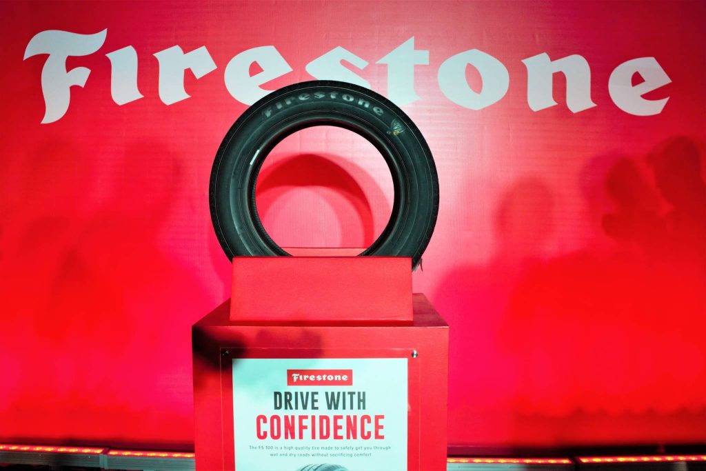 Black Firestone tire on stand with Drive with Confidence slogan red automotive wallpaper background