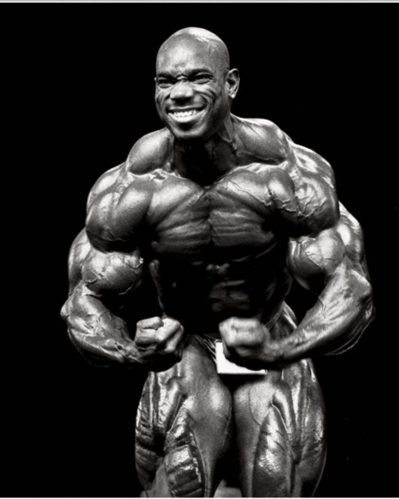 Flex Wheeler black and white wallpaper showcasing muscular definition and iconic smile
