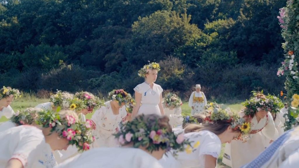 Florence Pugh as Dani in Midsommar wearing white dress and floral crown in ritual field Wallpaper