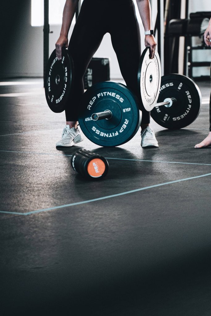 Focused athlete in modern gym with REP Fitness barbell and foam roller workout wallpaper background